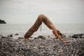 Young woman practicing yoga in downward facing dog pose on beach Royalty Free Stock Photo