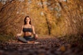 Young woman practicing yoga exercise at autumn park with yellow leaves. Sports and recreation lifestyle Royalty Free Stock Photo