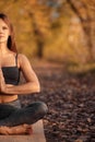 Young woman practicing yoga exercise at autumn park with yellow leaves. Sports and recreation lifestyle Royalty Free Stock Photo