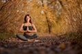 Young woman practicing yoga exercise at autumn park with yellow leaves. Sports and recreation lifestyle Royalty Free Stock Photo