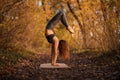 Young woman practicing yoga exercise at autumn park with yellow leaves. Sports and recreation lifestyle Royalty Free Stock Photo