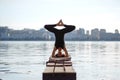 Young woman practicing yoga exercise at quiet wooden pier with city background. Sport and recreation in city rush Royalty Free Stock Photo