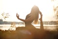 Young woman practicing yoga exercise at river beach and city background Royalty Free Stock Photo