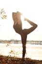 Young woman practicing yoga exercise at river beach and city background Royalty Free Stock Photo