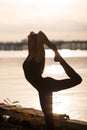 Young woman practicing yoga exercise at river beach and city background Royalty Free Stock Photo