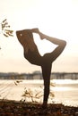 Young woman practicing yoga exercise at river beach and city background Royalty Free Stock Photo