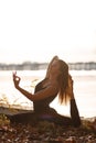 Young woman practicing yoga exercise at river beach and city background Royalty Free Stock Photo
