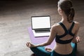 Young woman practicing yoga at home, online video training class, girl doing exercises and meditate Royalty Free Stock Photo