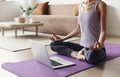 Young woman practicing yoga at home. Online video training. Girl doing exercises and meditate. Royalty Free Stock Photo