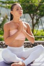 Young woman practicing yoga, meditating in half lotus pose with namaste. Royalty Free Stock Photo