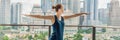 Young woman is practicing yoga in the morning on her balcony with a panoramic view of the city and skyscrapers BANNER, long format Royalty Free Stock Photo