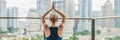 Young woman is practicing yoga in the morning on her balcony with a panoramic view of the city and skyscrapers BANNER, long format Royalty Free Stock Photo