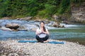 Young woman is practicing yoga at mountain river