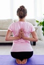 Young woman practicing yoga with namaste behind back at home indoor. Girl doing reverse prayer pose, back and shoulders stretching Royalty Free Stock Photo