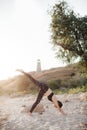 Young Woman Practicing yoga in the nature at sunset on sand beach against of lighthouse. Downward Facing Dog Pose Adho Royalty Free Stock Photo