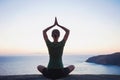 Young woman practicing yoga near the sea