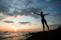 Young woman practicing yoga on the ocean coast during a amazing sunset Royalty Free Stock Photo