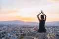 Young woman practicing yoga outdoors at sunset with a big city at the background. Harmony, meditation and healthy lifestyle concep Royalty Free Stock Photo