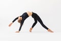 A young woman practicing yoga performs the exercise of Kamatkarasana, the pose of a dancing dog, trains in black sportswear Royalty Free Stock Photo