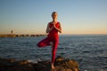 Young woman practicing yoga on the pier near the sea. Royalty Free Stock Photo