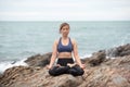 Young woman practicing yoga on a rock at the beach