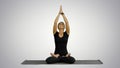 Young woman practicing yoga, sitting in a lotus position, meditating with closed eyes on white background Royalty Free Stock Photo