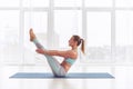 Young woman practicing yoga, sitting in Paripurna Navasana exercise at the yoga studio