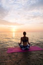 Young woman practicing yoga, sitting on pier, by the sea Royalty Free Stock Photo