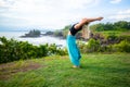 Young woman practicing yoga, standing in Hasta Uttanasana pose, deflection back. Outdoor yoga on the cliff. Yoga retreat. Tanah