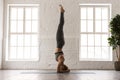 Young woman practicing yoga, standing in headstand pose, salamba sirsasana