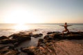 Young woman practicing yoga, standing in Virabhadrasana pose on the beach. Sunset time. Tegal Wangi beach, Bali Royalty Free Stock Photo