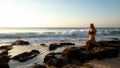 Young woman practicing yoga, standing in Virabhadrasana pose on the beach. Sunset time. Tegal Wangi beach, Bali Royalty Free Stock Photo