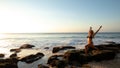 Young woman practicing yoga, standing in Virabhadrasana pose on the beach. Sunset time. Tegal Wangi beach, Bali Royalty Free Stock Photo