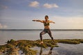 Young woman practicing yoga, standing in Virabhadrasana pose. Outdoor yoga at the beach. Warrior pose. Bali, Indonesia Royalty Free Stock Photo