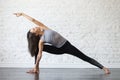 Young attractive woman in Utthita parsvakonasana pose, studio ba