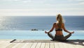 Young woman practicing yoga by a swimming pool with ocean in the background. Royalty Free Stock Photo