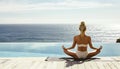 Young woman practicing yoga by a swimming pool with ocean in the background. Royalty Free Stock Photo