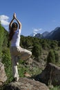 Young woman is practicing yoga in Tree Pose Vrikshasana pose at mountain Royalty Free Stock Photo