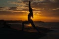 Young woman practicing yoga warrior and hero pose at sunset, sunrise . Zen wellness and wellbeing concept. Royalty Free Stock Photo