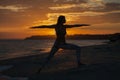 Young woman practicing yoga warrior and hero pose at sunset, sunrise . Zen wellness and wellbeing concept. Royalty Free Stock Photo