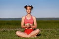 Young woman practising yoga meditation with her pet hedgehog on green grass at park in summer. Relax and harmony Royalty Free Stock Photo