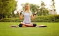 Young woman practising yoga pose at the park on a beautiful green field