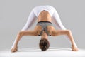 Young woman in Prasarita Padottanasana pose, grey studio backgro Royalty Free Stock Photo