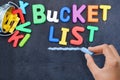 Young woman prepared for bucket list with metallic bucket and colorful plastic letters on blackboard Royalty Free Stock Photo