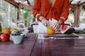 young woman preparing a healthy recipe of diverse fruits, watermelon, orange and blackberries. Using a mixer. Homemade, indoors,