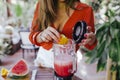 young woman preparing a healthy recipe of diverse fruits, watermelon, orange and blackberries. Using a mixer. Homemade, indoors,