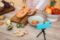 Young woman preparing healthy salad while streaming online for webinar lesson - Influencer girl making smoothie doing video