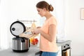 Young woman preparing mushrooms with modern multi cooker