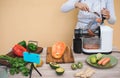 Young woman preparing organic juice with cold pressed extractor machine - Girl making smoothie with vegetables and fruit - Healthy