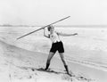 Young woman preparing to throw a javelin on the beach Royalty Free Stock Photo